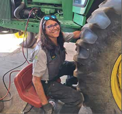 Ellie Kippes, service technician from Longmont, Colorado, working on a tractor.